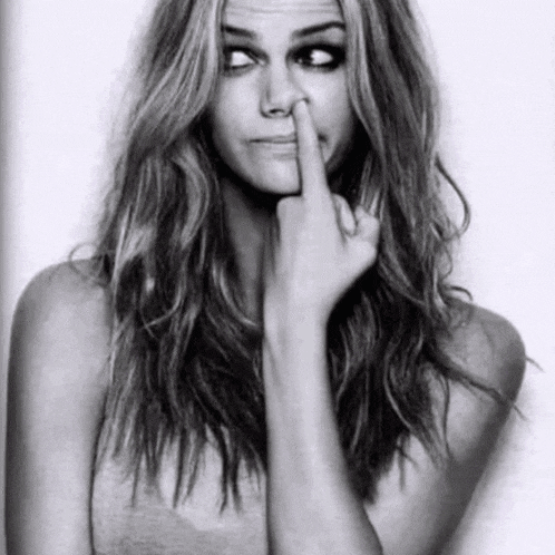 a black and white photo of a woman making a funny face and giving the middle finger .