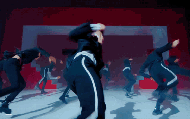 a group of people are dancing in front of a red and white wall