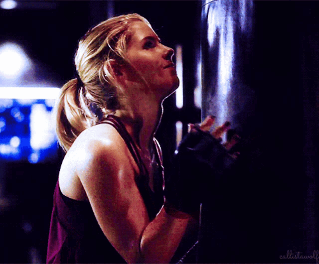 a woman is leaning against a punching bag with the words " cellistabull " on the bottom right