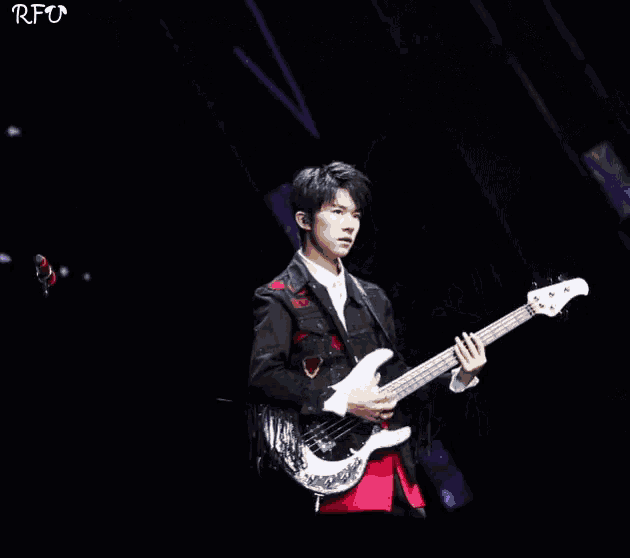 a man in a suit is playing a guitar on stage .
