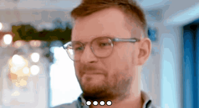 a man with glasses and a beard is looking at something