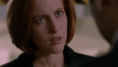 a woman with red hair and blue eyes is looking at a man with a serious look on her face .