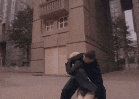 a man is carrying a woman in his arms in front of a large building