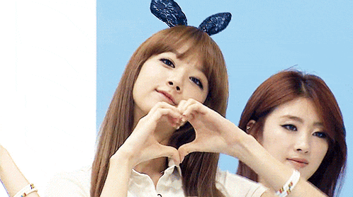 a girl wearing bunny ears makes a heart with her hands
