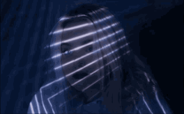 a woman 's face is covered by a blue light beam