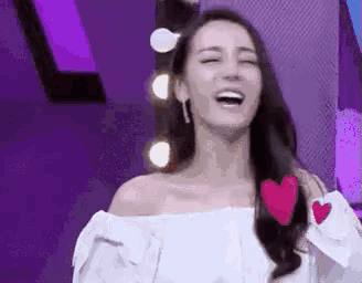 a woman is holding a red heart in her hair and smiling .