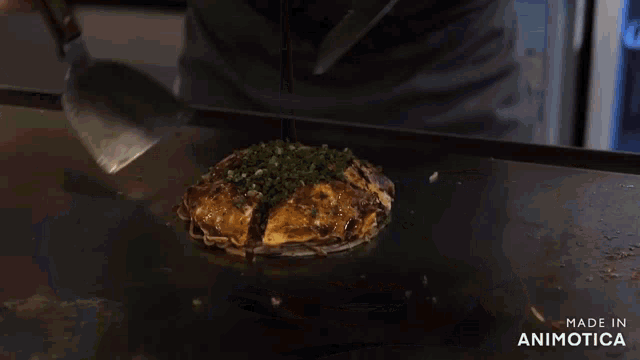 a person is holding a spatula over a plate of food with the words made in animotica below them
