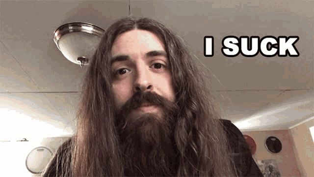a man with long hair and a beard has the word i suck above him