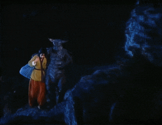 a person standing next to a monster with horns