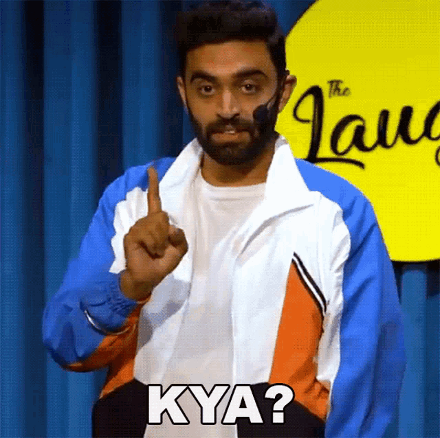 a man in a colorful jacket is pointing up and says kya