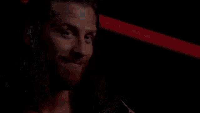a man with long hair and a beard is smiling and looking at the camera .