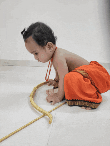 a baby in a red skirt is playing with a bow and arrow