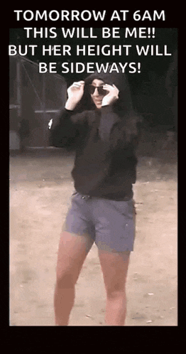 a woman wearing sunglasses and a hoodie is standing on a dirt road .