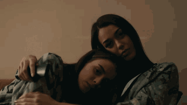 two women are hugging each other with one holding a cell phone