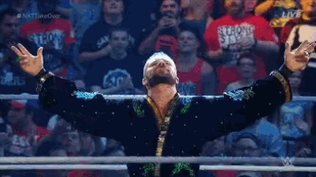a wrestler with his arms outstretched in front of a crowd with a shirt that says strong style