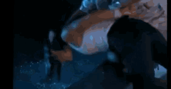 a man is swimming underwater in a pool with a light coming out of his mouth .