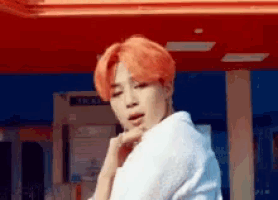 a young man with red hair is standing in front of a ticket booth .