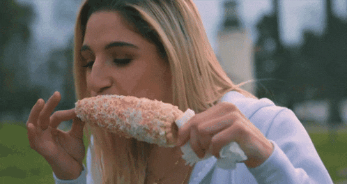 a woman eating a corn on the cob with sprinkles on it