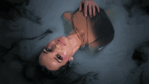 a woman laying in a bathtub with smoke coming out of it