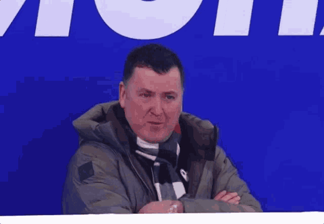 a man in a jacket and scarf is clapping his hands