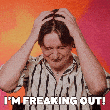 a man in a striped shirt has his hands on his head and the words i 'm freaking out above him