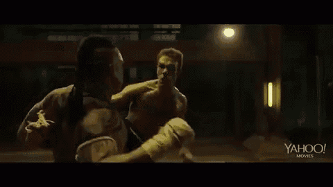 two men are fighting each other in a dark room in a boxing match .