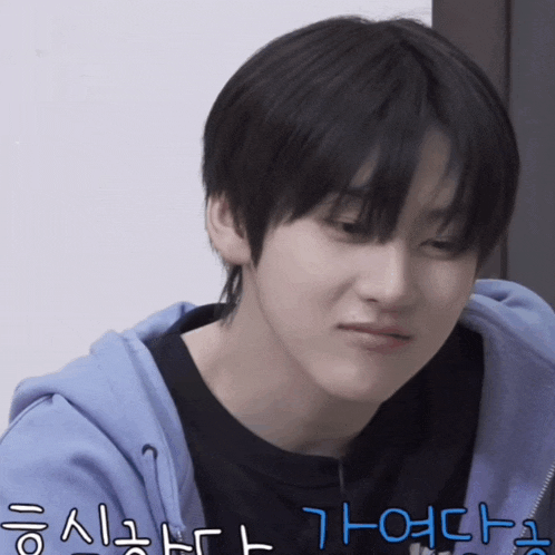 a young man wearing a black shirt and a blue hoodie has korean writing on his face