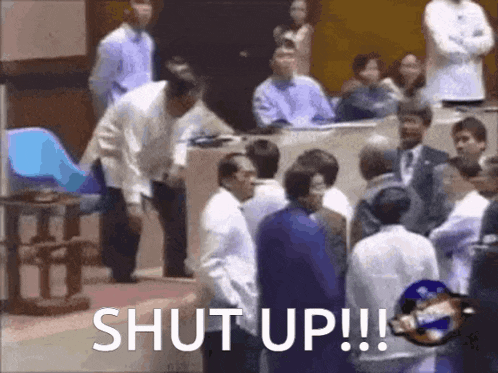 a group of people are standing in a room with the words shut up !!! written on the bottom