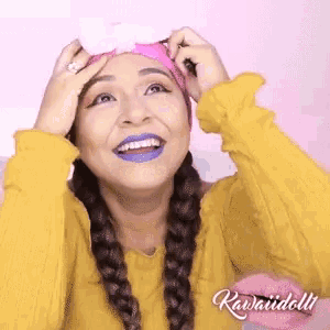 a woman wearing a yellow sweater and a pink headband is smiling