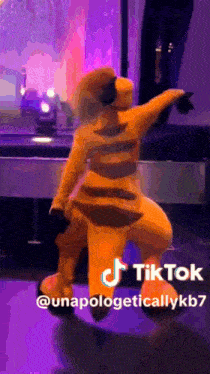 a mascot is dancing on a stage in front of a purple background