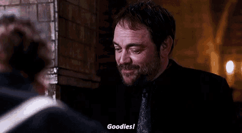 a man in a black suit and tie is smiling and saying goodies .