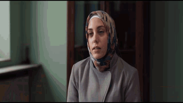 a woman wearing a hijab is sitting in a room