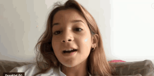 a young girl is sitting on a couch and the word duraklat is on the bottom