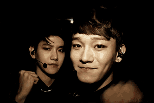 two young men are posing for a picture and one has a microphone on his ear
