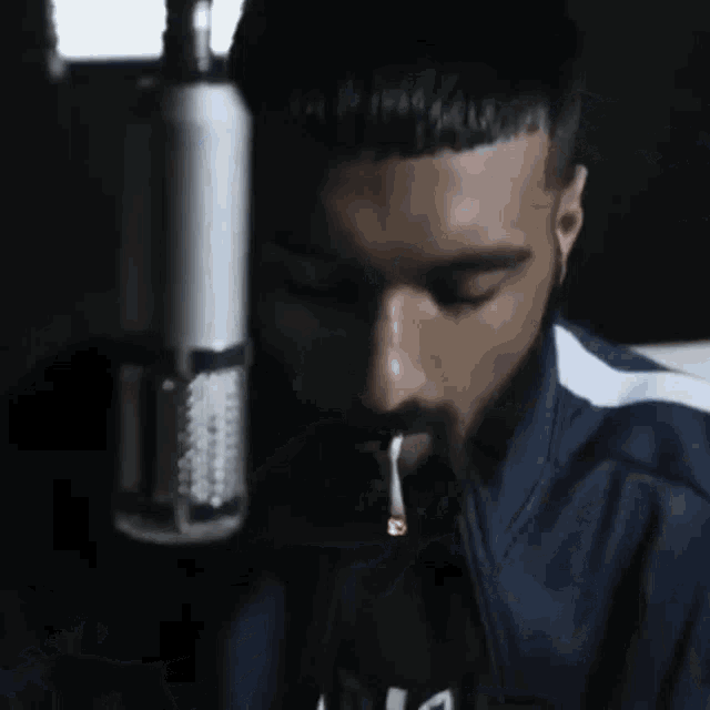 a man is smoking a cigarette in front of a microphone