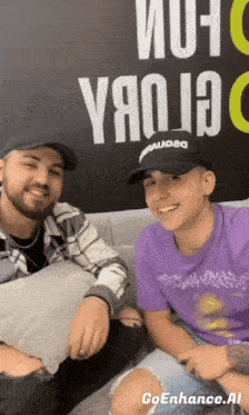 two men sitting on a couch in front of a wall that says goenhance.ai