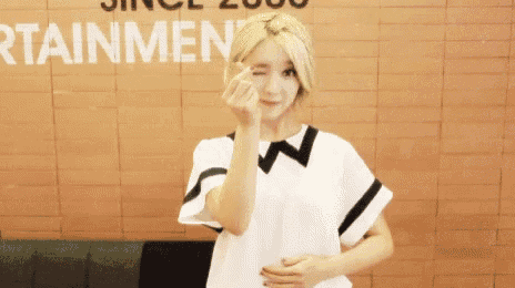 a girl in a white shirt is making a heart shape with her hand .
