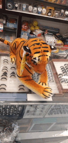 a stuffed tiger is on display in a store with watches and rings