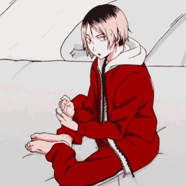 a boy in a red hoodie is sitting on a bed