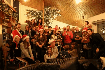 a group of people wearing santa hats pose for a picture in front of a christmas tree