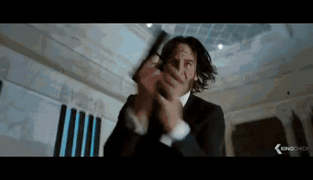 a man in a suit is holding a gun in his hand and shooting it .