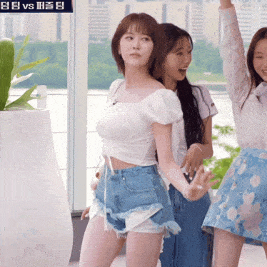 a woman in a white top and denim shorts is standing next to another woman
