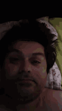 a man with a beard is laying on a bed with his eyes closed