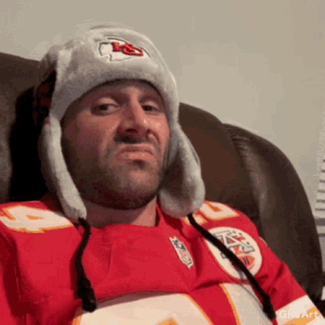 a man wearing a kansas city chiefs jersey and a hat