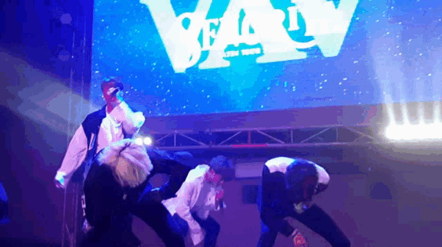 a group of people are performing on stage in front of a large screen that says " party "