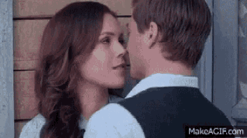 a man and a woman are kissing each other in front of a door .