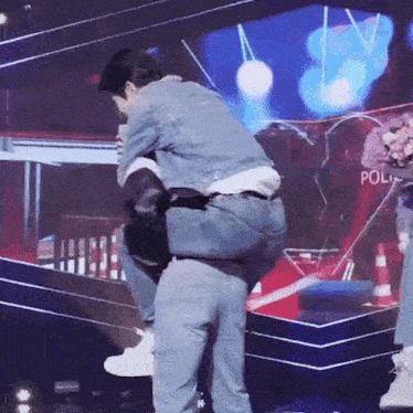 a man in a denim jacket is carrying another man on his shoulders .