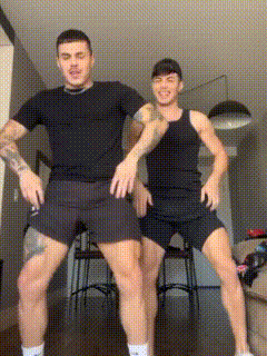 two men are standing next to each other in a living room and dancing .