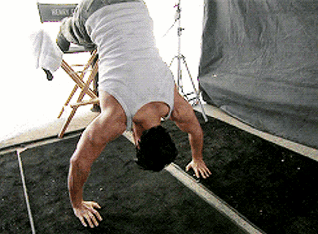 a man is doing a handstand in front of a chair that has the word ready on it