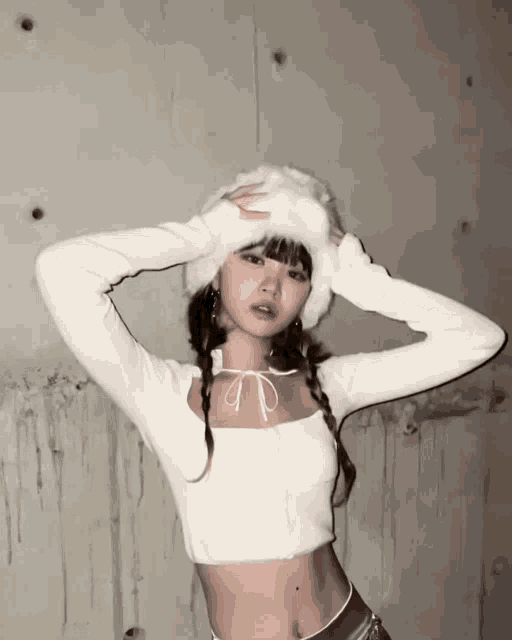 a woman wearing a white crop top and a white hat
